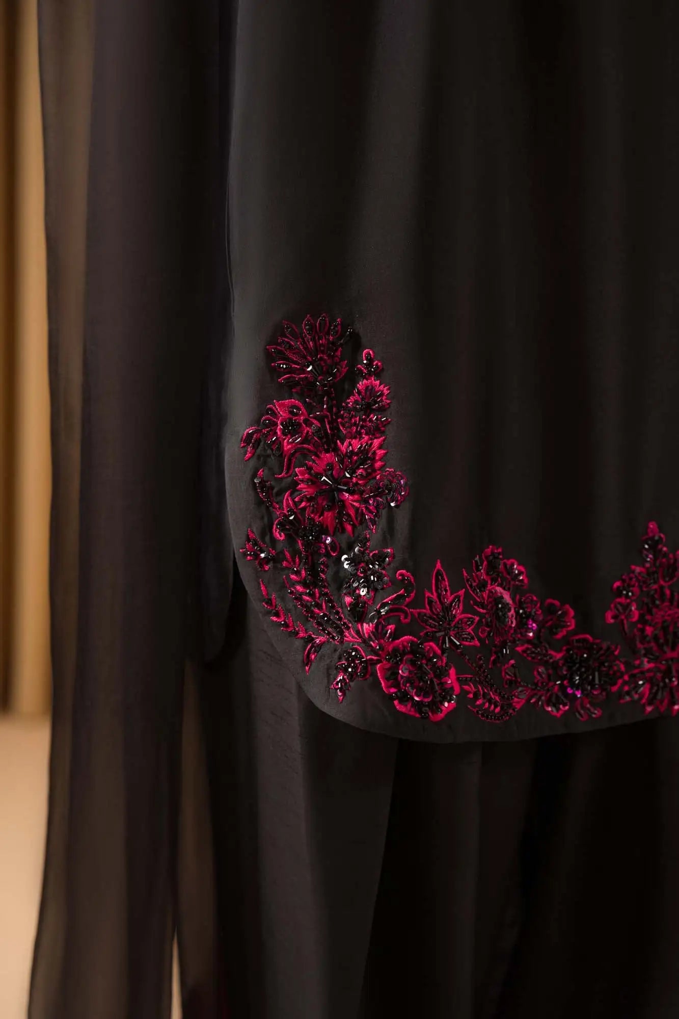 Black fabric with red floral embroidery on a plain background