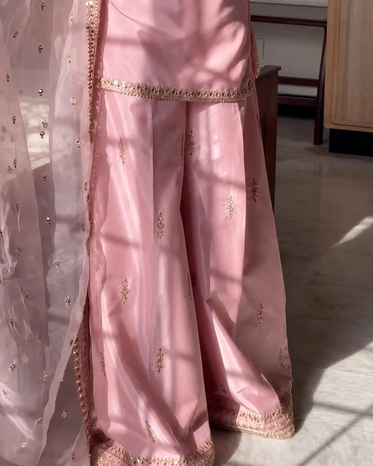 Pink saree with gold embroidery on a light background