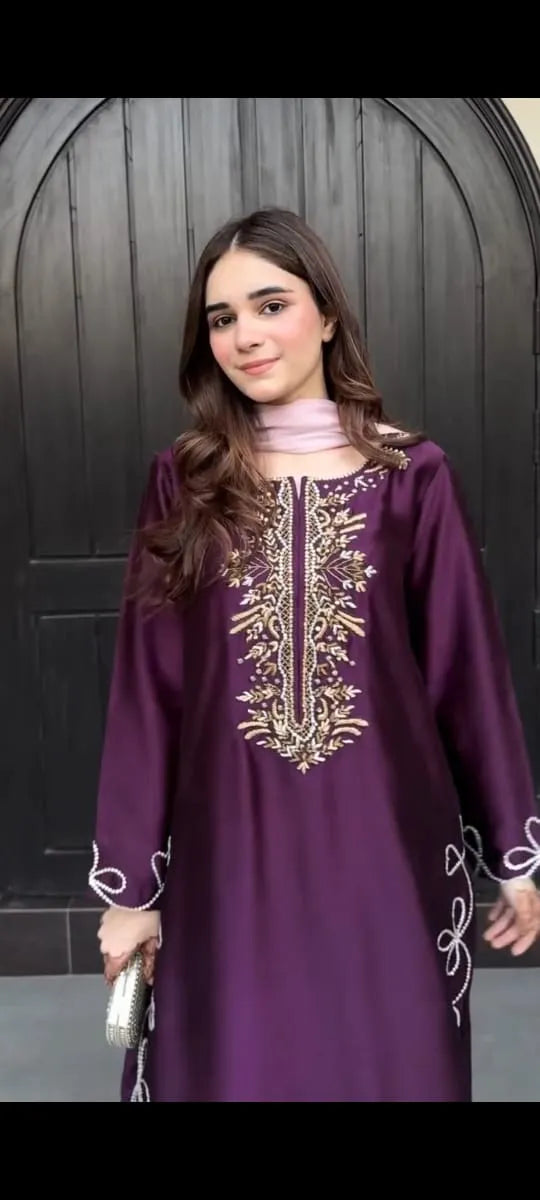 Woman wearing a purple embroidered dress against a dark background