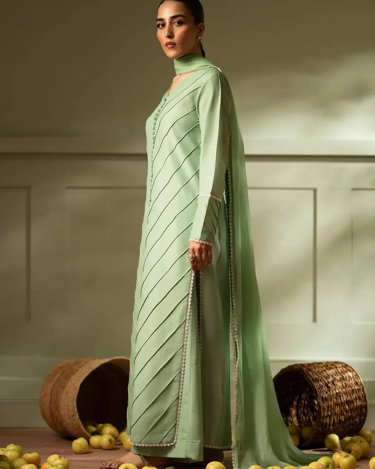 Woman wearing a light green traditional outfit with a plain background