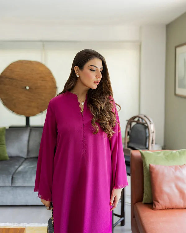 Woman in a pink dress standing in a living room with a couch and wall art.