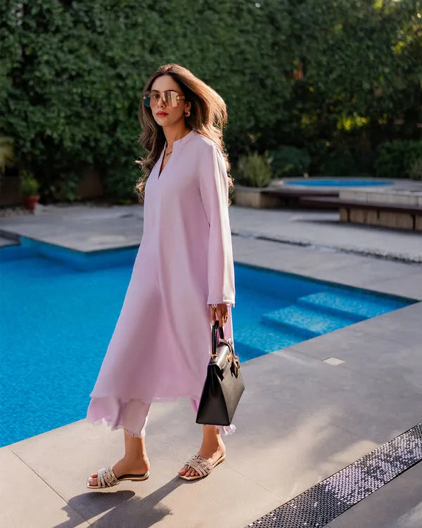 Woman in a light pink dress standing by a pool