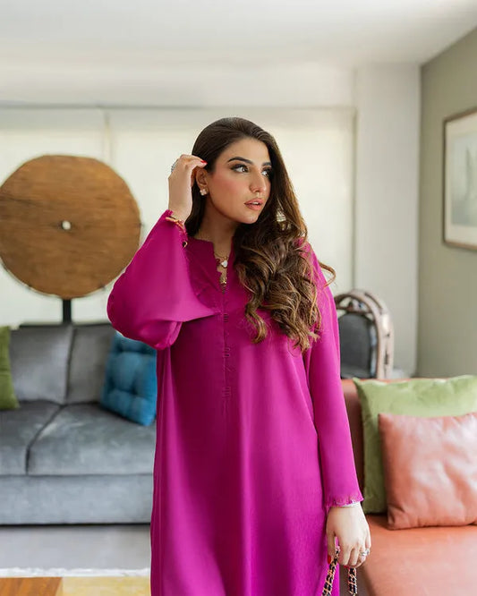 Woman in a pink dress standing in a living room with a gray sofa and colorful pillows.