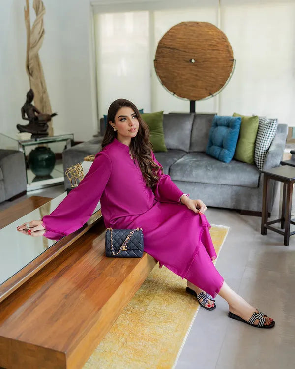 Woman in a pink dress sitting on a wooden bench in a modern living room.