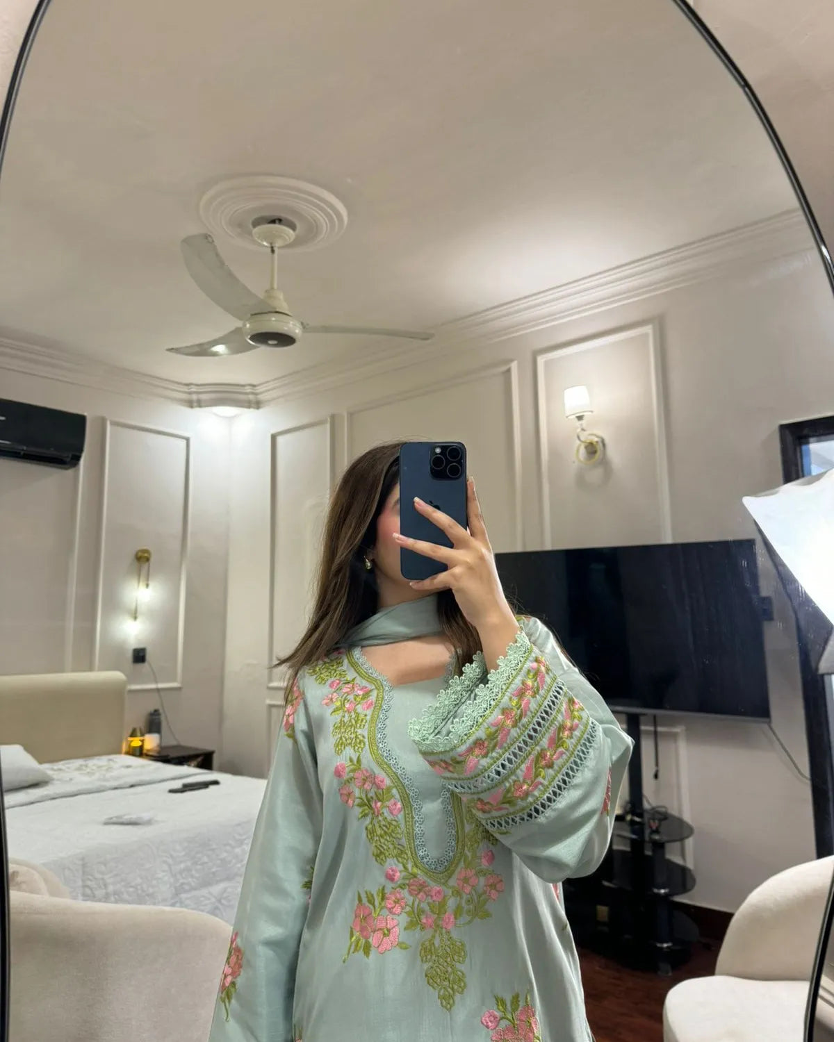 Person taking a mirror selfie in a room with decorative walls and furniture.