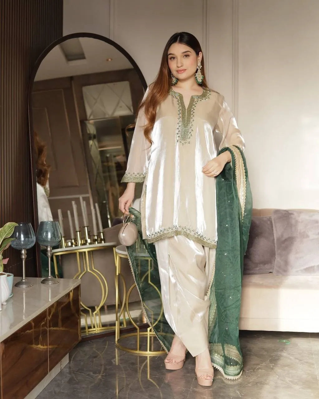 Woman in a traditional outfit with green and white design in a modern interior setting