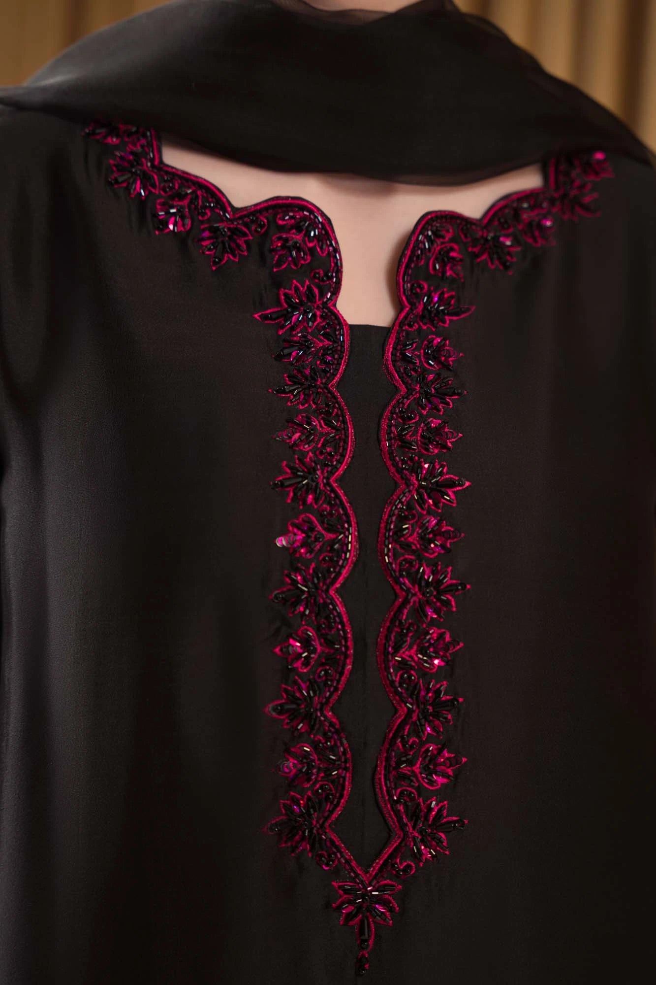 Black garment with red embroidery on a plain background
