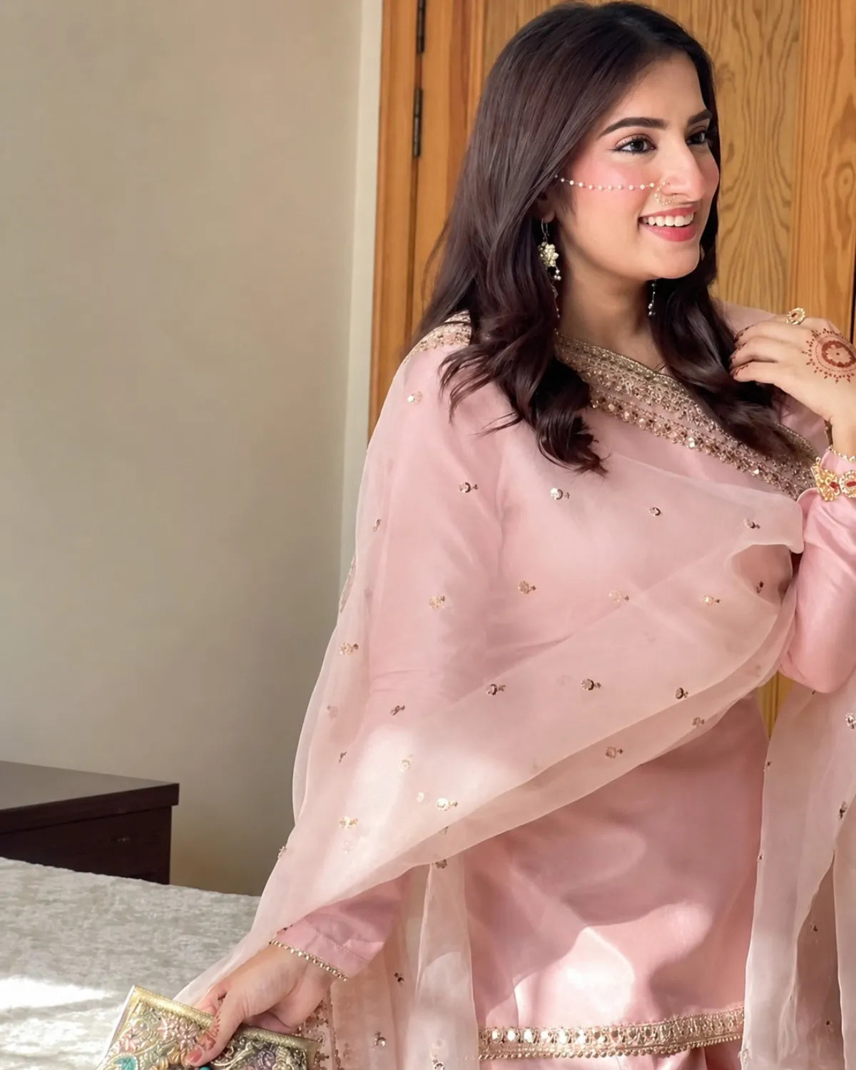 Woman wearing a pink traditional outfit with gold details indoors.