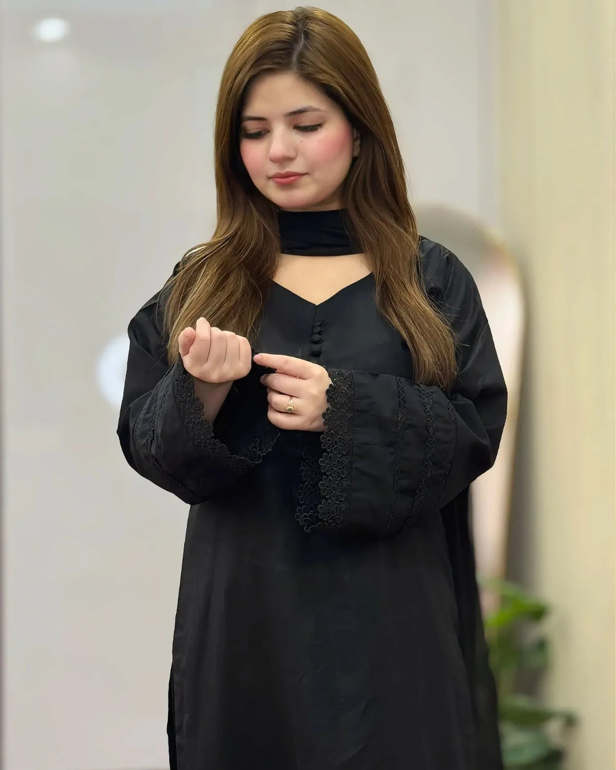 Woman wearing a black outfit with lace details in an indoor setting