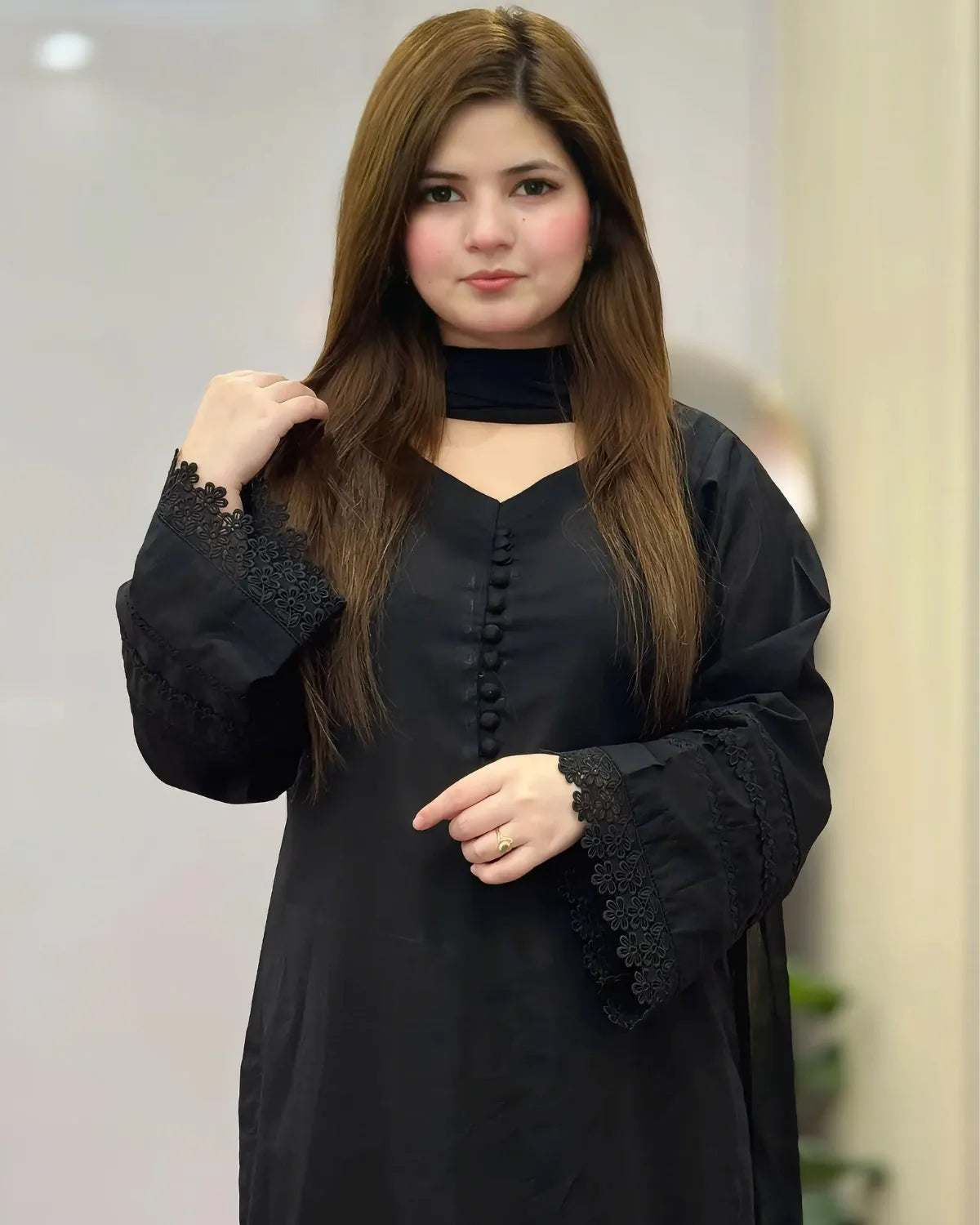 Woman wearing a black outfit with lace details indoors