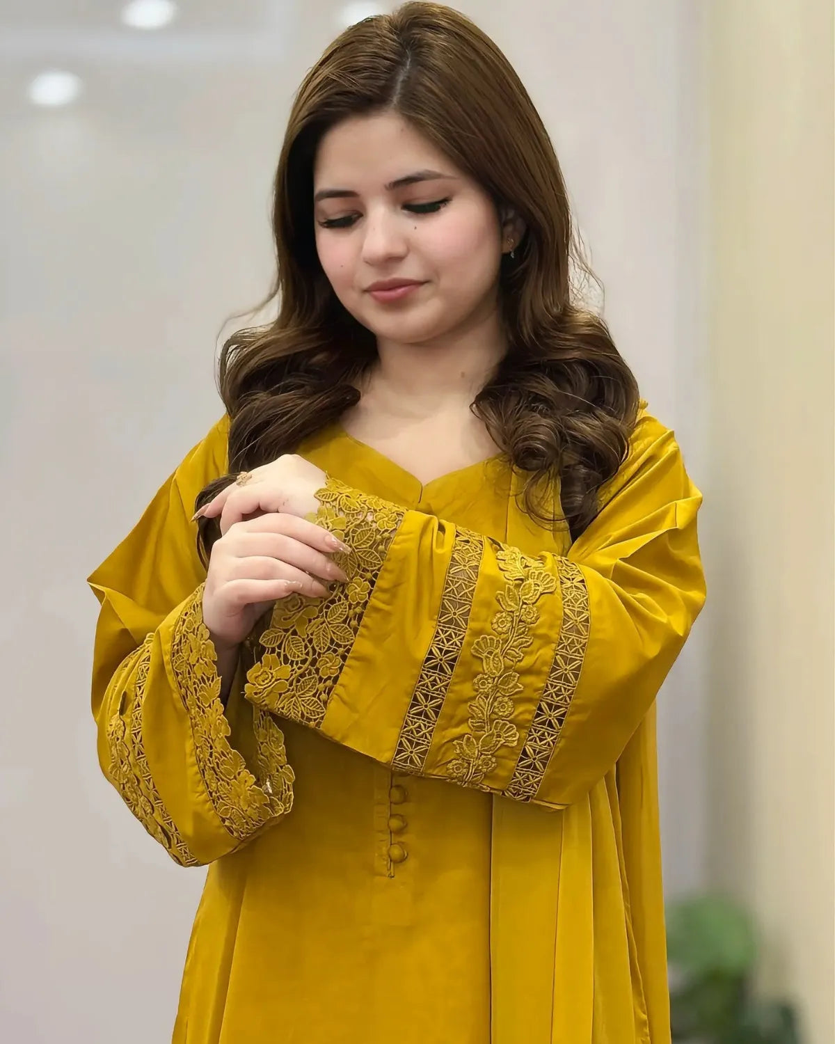 Woman wearing a yellow outfit with intricate designs, indoors.