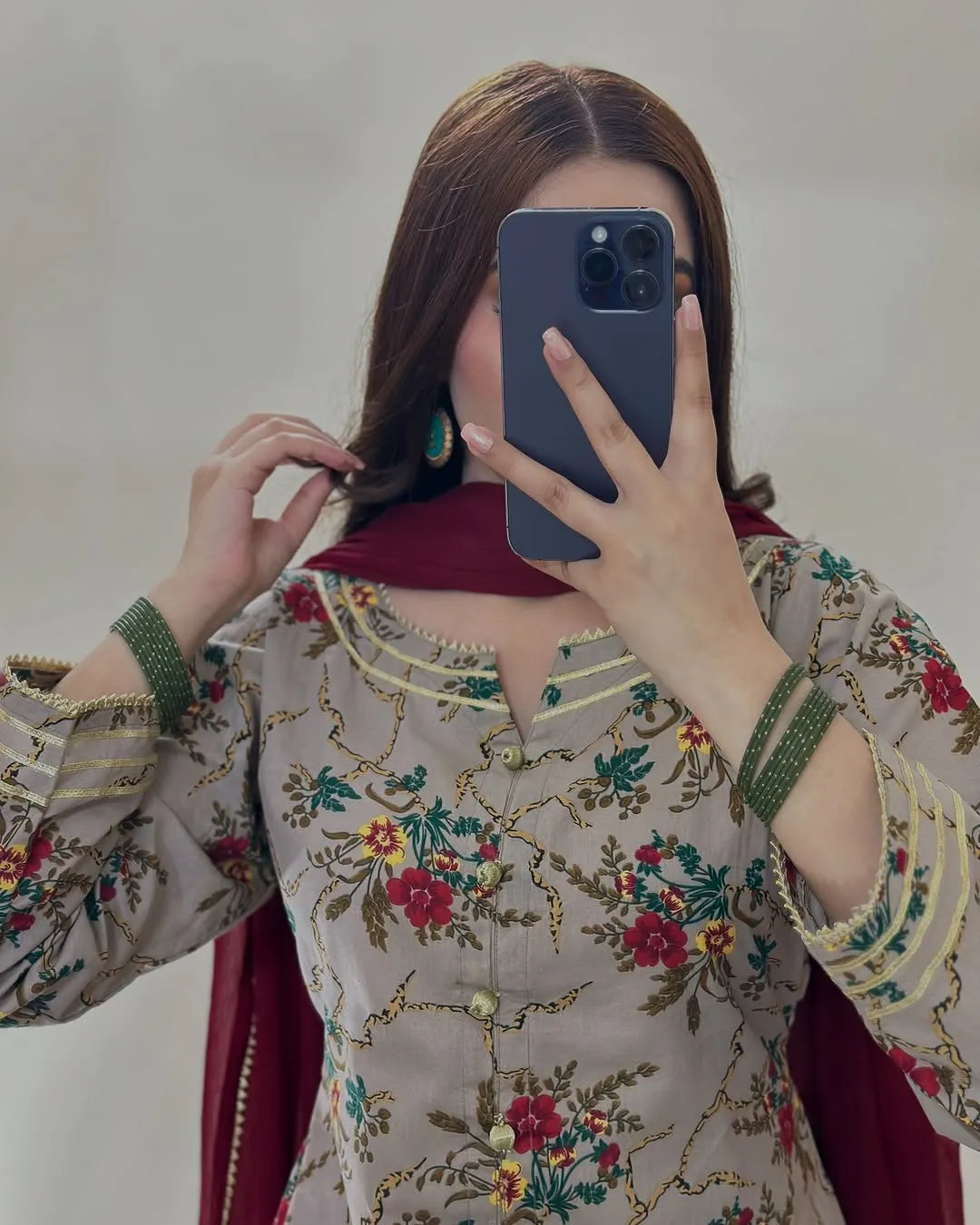 Person wearing a traditional embroidered outfit taking a mirror selfie.