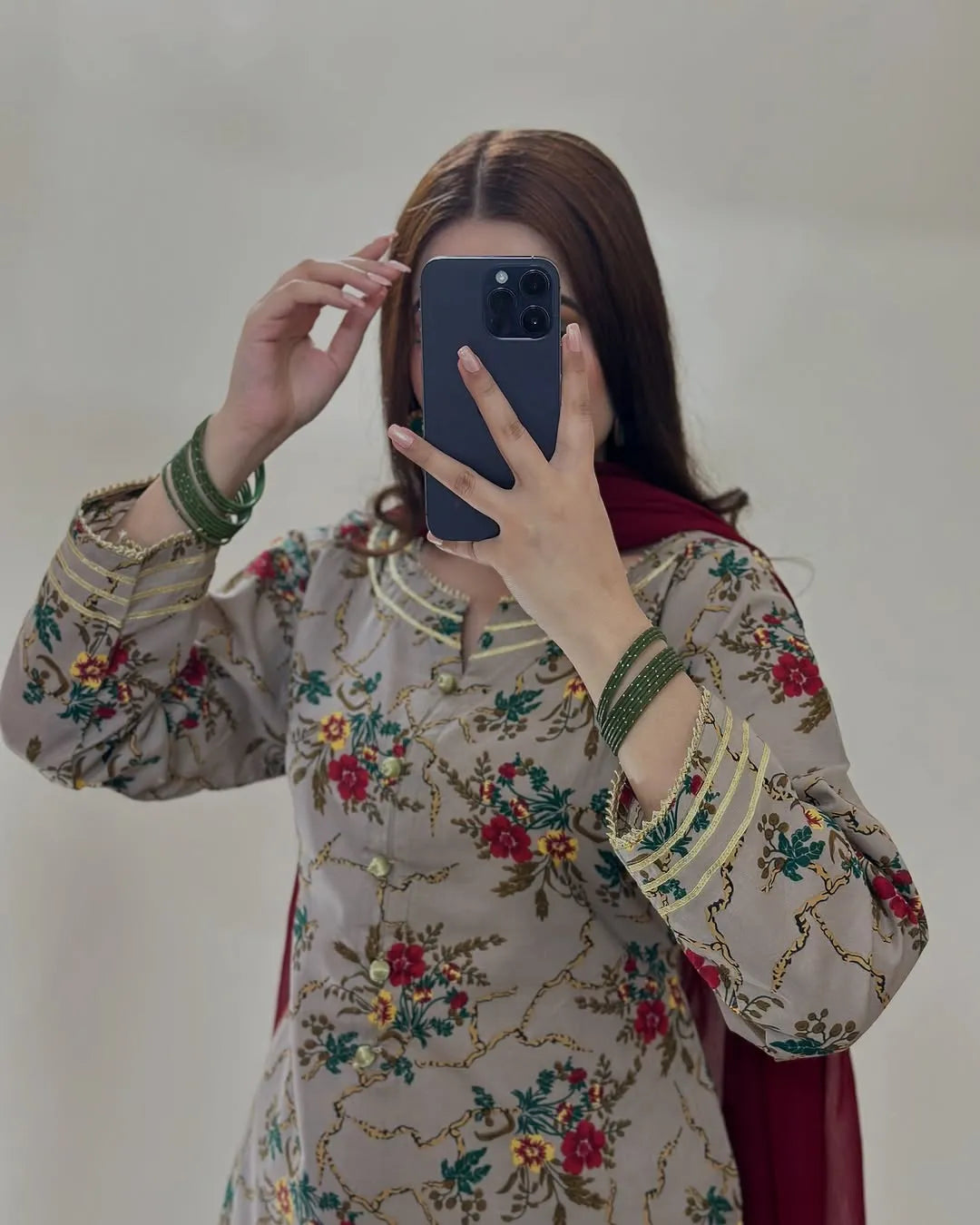 Person wearing a floral embroidered outfit taking a mirror selfie.