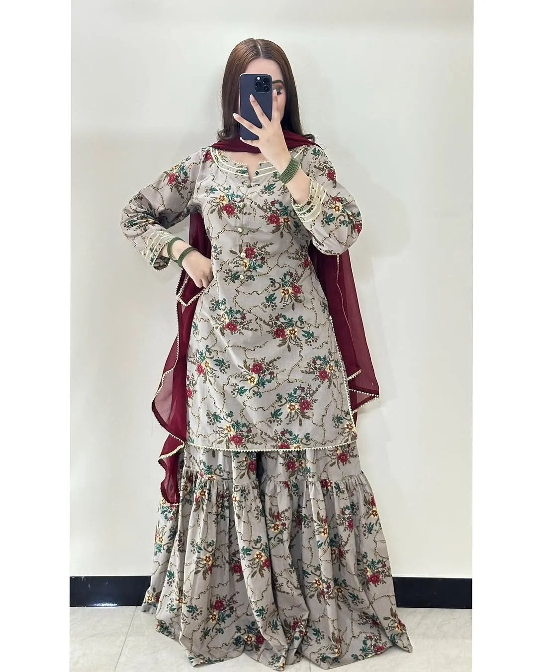 Person wearing a floral dress with a maroon dupatta against a white background