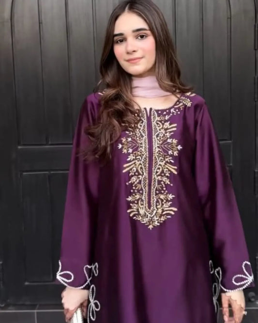 Woman wearing a purple embroidered dress against a black background