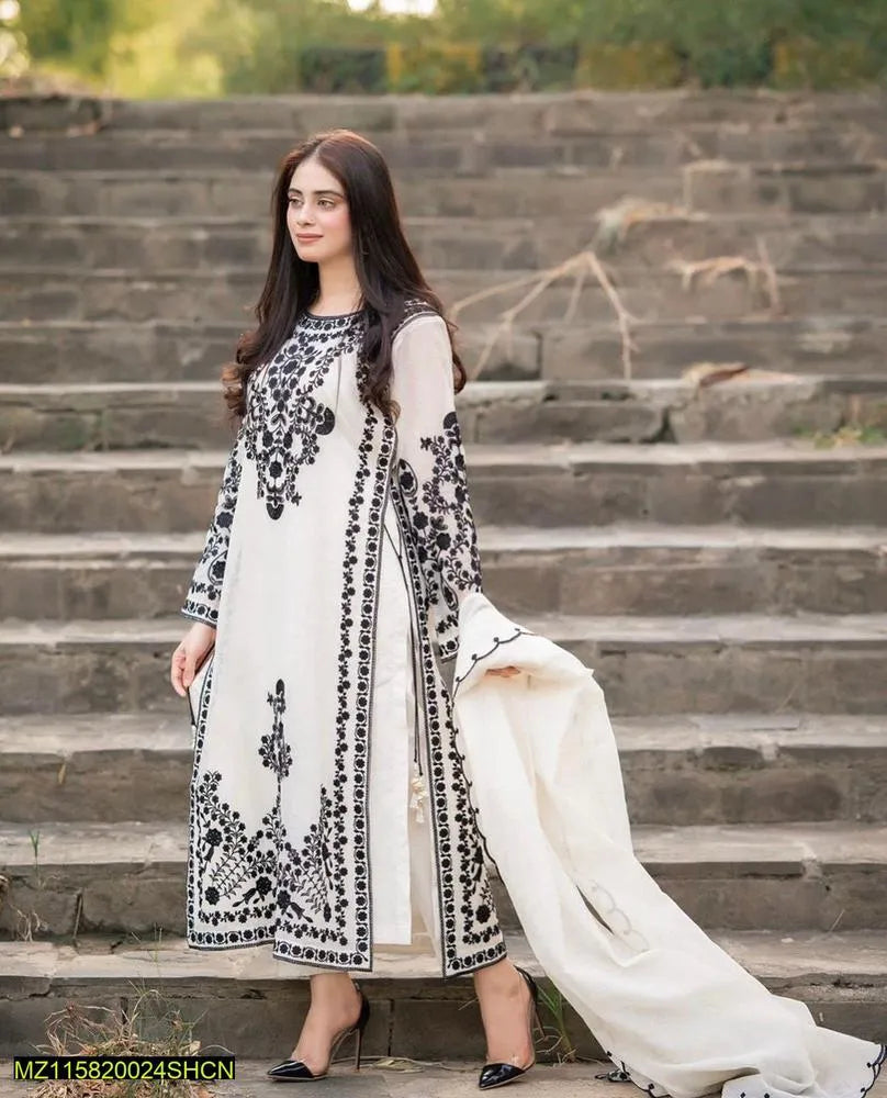 Woman in a white and black embroidered outfit standing on stone steps outdoors.