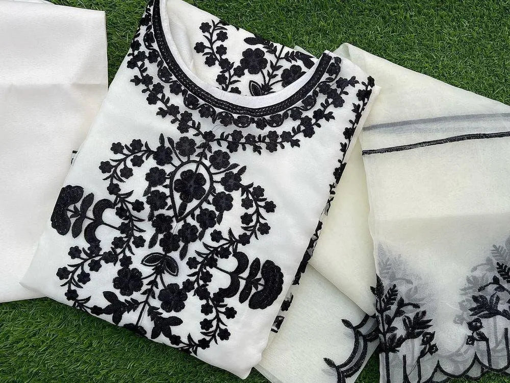 White fabric with black floral embroidery on a green grass background