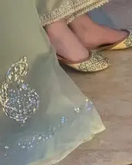 Close-up of a person wearing high-heeled shoes with a decorative anklet and earrings.