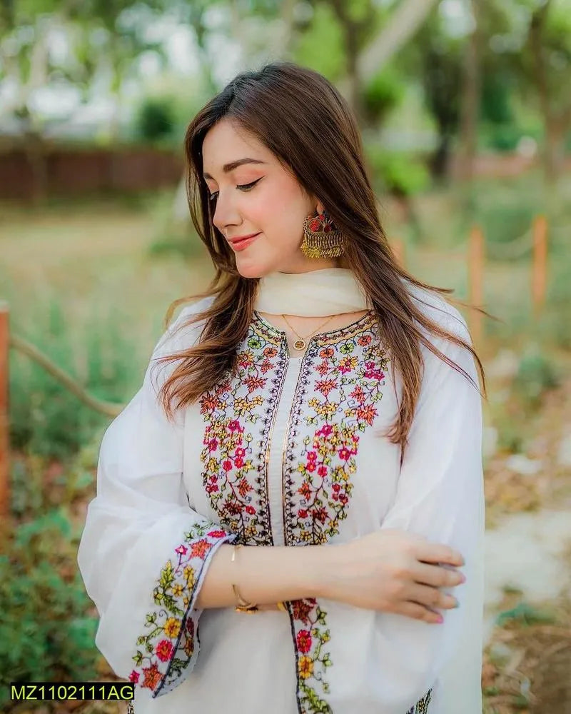 Woman wearing a white embroidered outfit with a blurred natural background