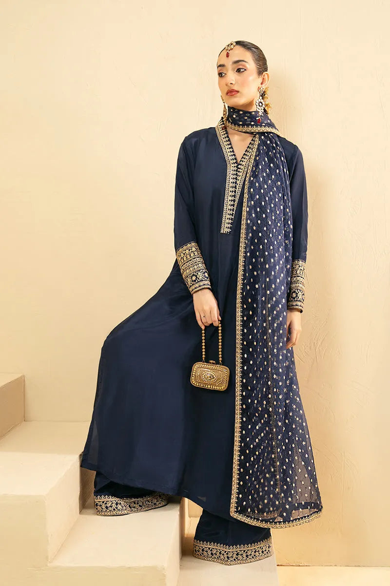 Woman in a navy blue traditional outfit with gold accents against a beige background