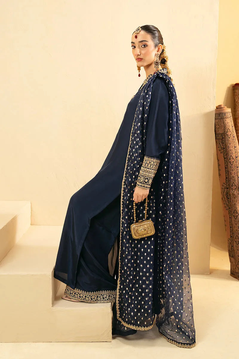 Woman in a navy blue traditional outfit with gold embroidery on a beige background
