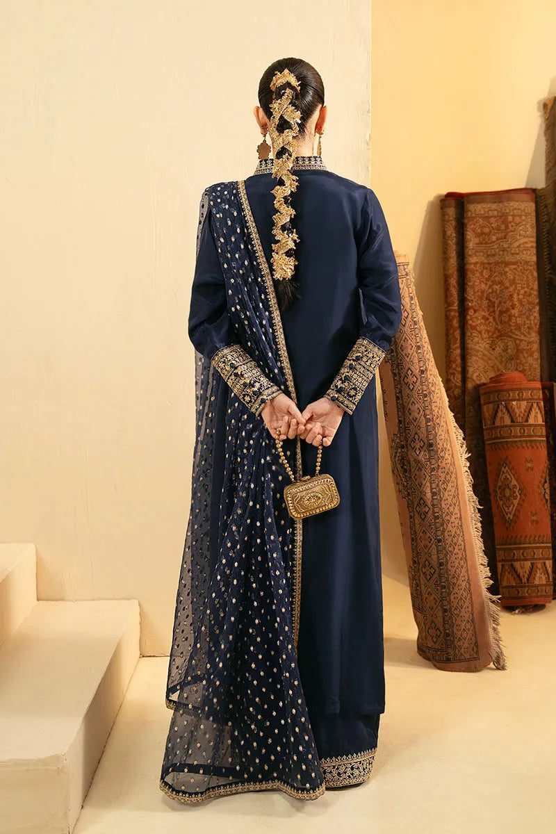 Person wearing a traditional blue outfit with gold details in an indoor setting.