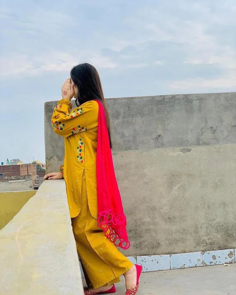 Woman in yellow traditional outfit with a red dupatta on a rooftop