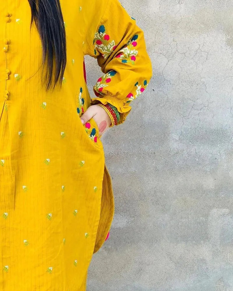 Yellow embroidered traditional outfit on a plain background