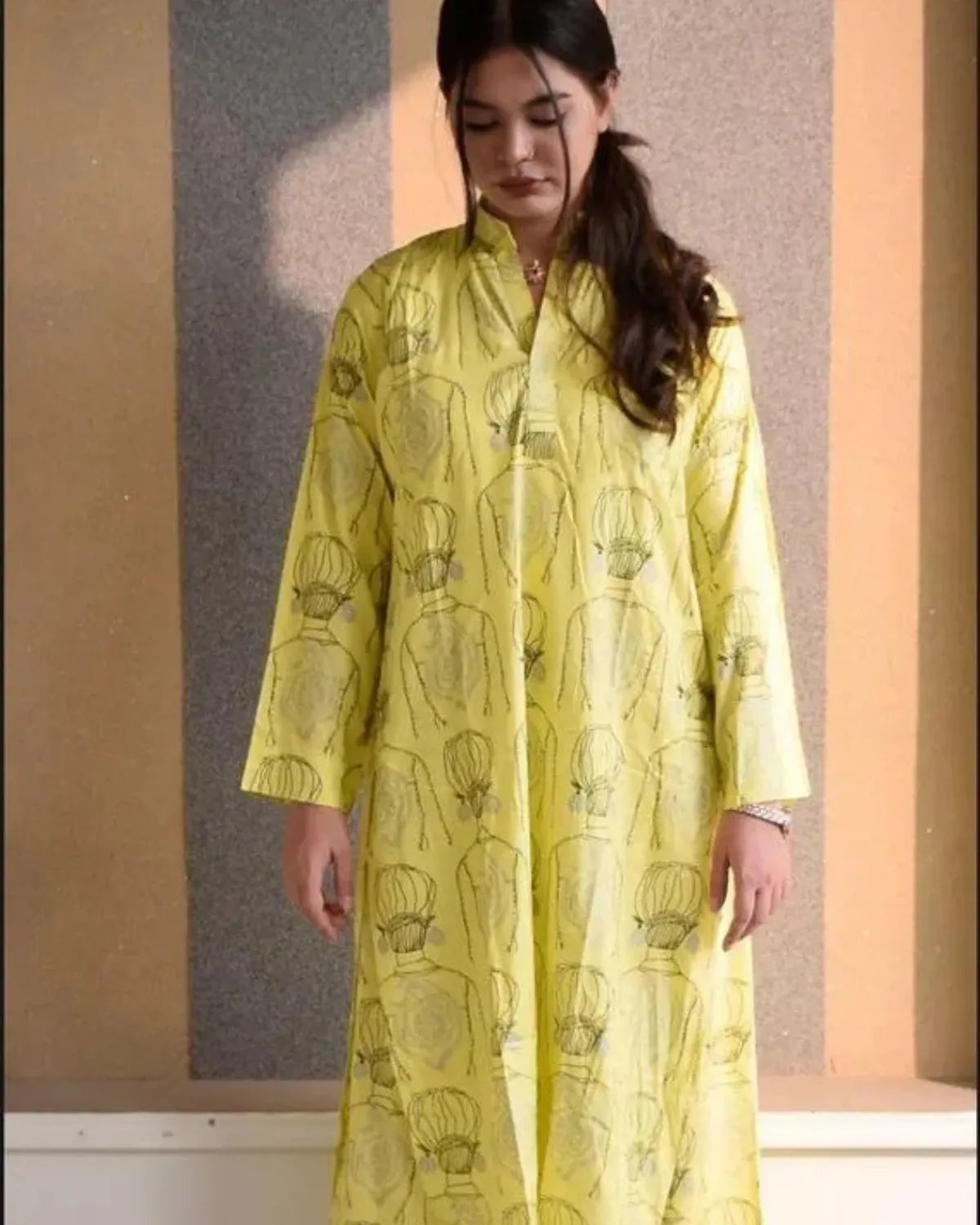 Woman wearing a yellow patterned dress against a plain background