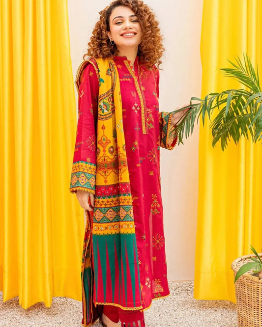 Woman in a colorful traditional outfit standing in front of yellow curtains with a plant.
