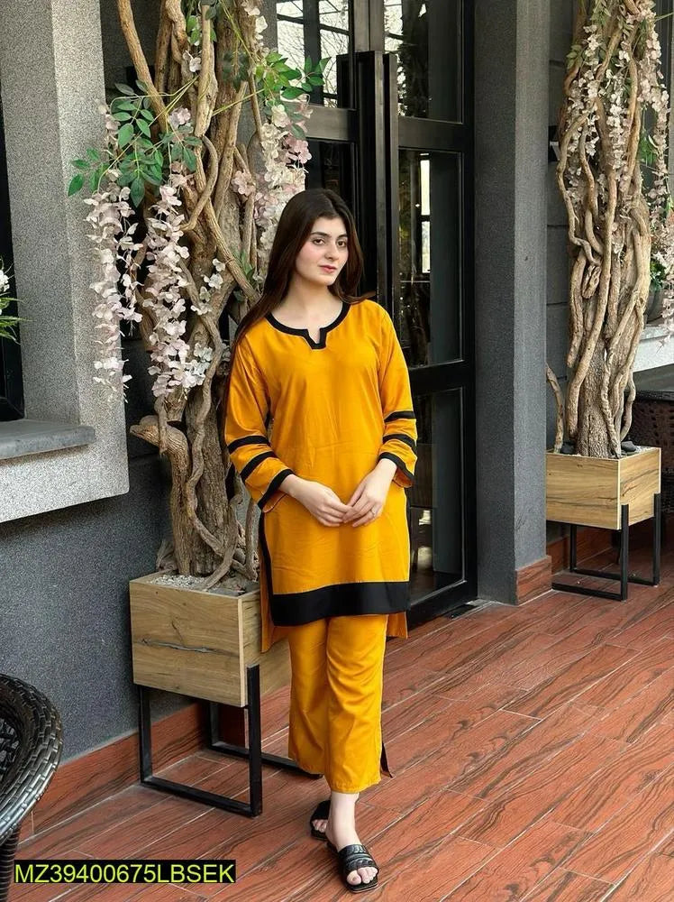 Woman in a yellow outfit standing in an indoor setting with plants and wooden flooring.
